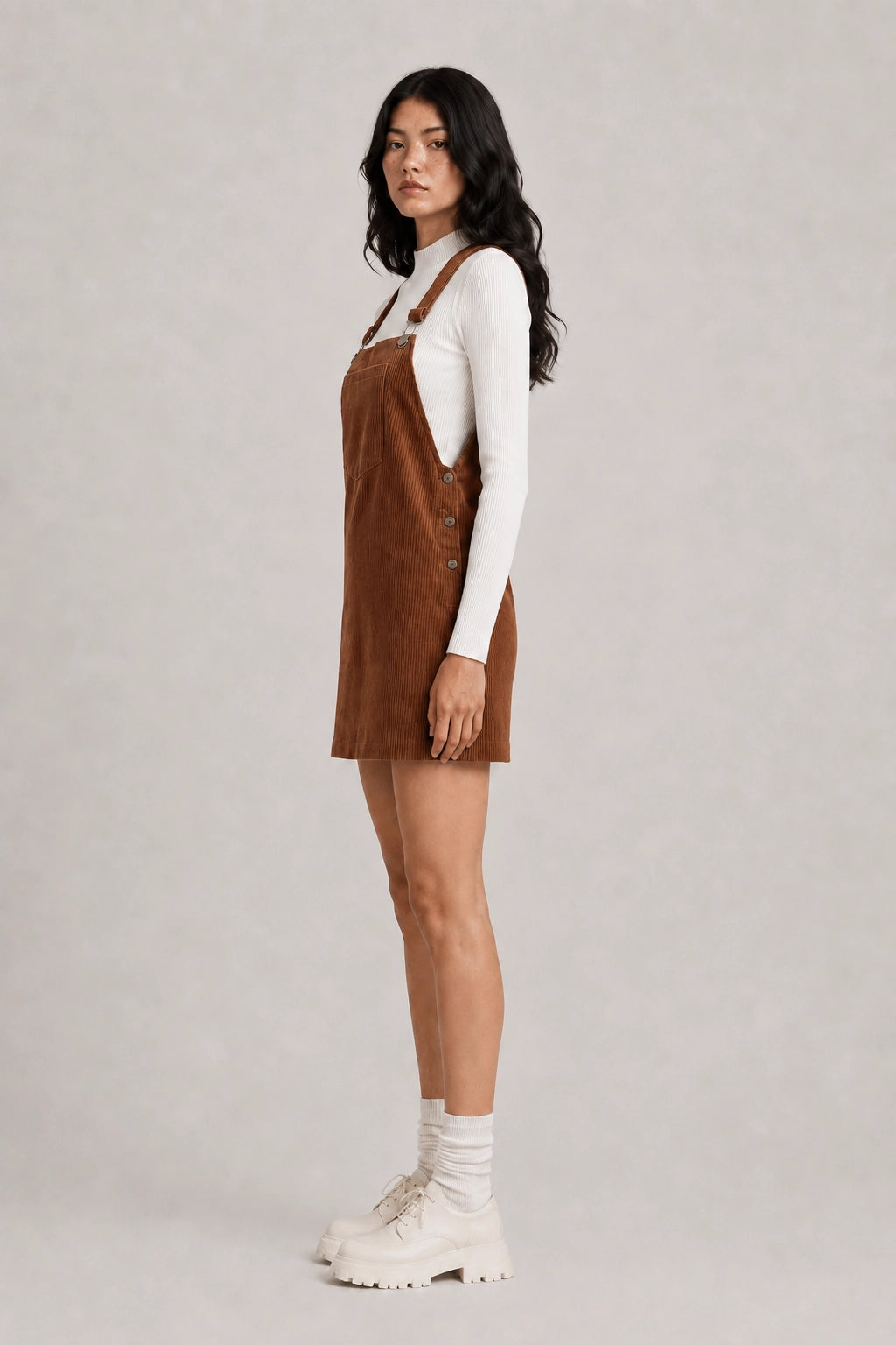 Brown pinafore dress with buttons at front and square neckline over white sleeves