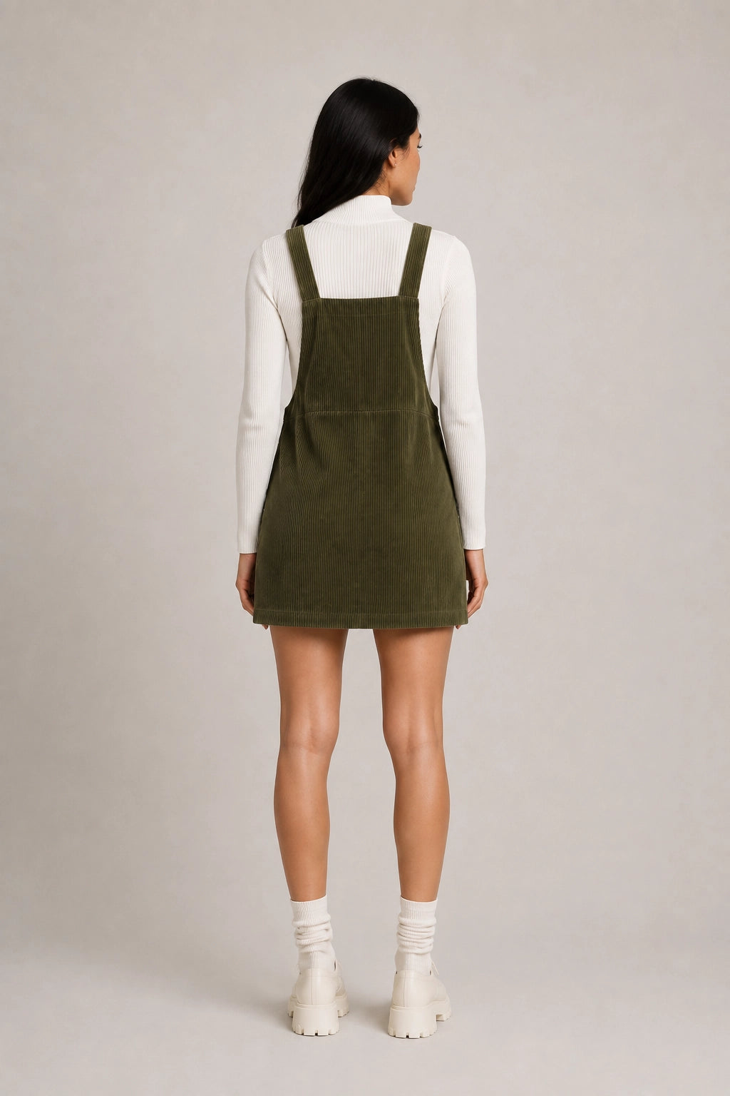Olive green pinafore dress from back view with adjustable shoulder straps