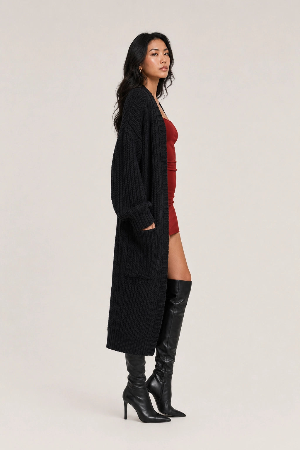 Black long cardigan with open front and side pockets, worn with black boots